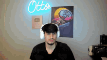 a man wearing headphones stands in front of a neon sign that says " otto "
