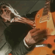 a man in a suit is playing a guitar with the letter l on it