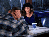 a man and a woman are sitting at a table with a cup that says ' ice cream ' on it