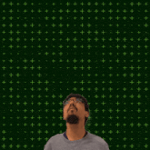 a man with glasses looks up at a glowing number 16