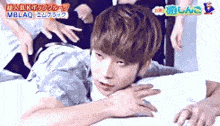 a young man is laying on his stomach on a bed surrounded by people 's hands .