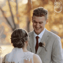 a bride and groom are smiling at each other in front of a sign that says hop pilly