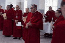 a group of priests in red robes are standing in a line