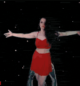 a woman in a red dress is dancing in front of a pair of giant hands