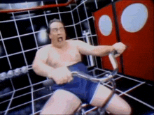a shirtless man is riding an exercise bike in a room with red doors .