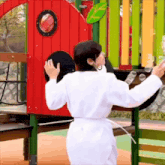a woman in a white robe is blowing soap bubbles in a playground
