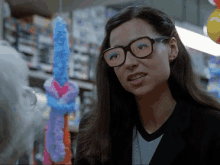 a woman wearing glasses is standing in front of a display of balloons