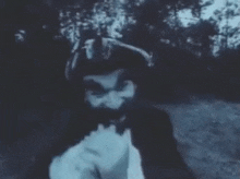 a man with a beard is covering his face with his hands in a black and white photo .