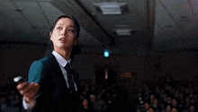 a woman is holding a gun in front of a crowd of people .