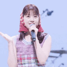 a woman singing into a microphone wearing a head scarf around her head