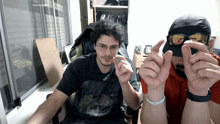 a man wearing glasses and a hat is sitting next to another man