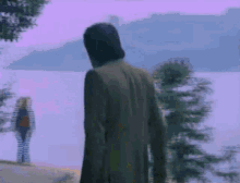 a blurry picture of a man and a woman looking at a body of water
