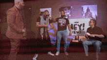 a group of men standing in front of a sign that says aew hey
