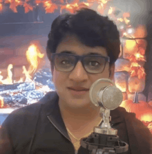 a man wearing glasses is holding a microphone in front of a fire