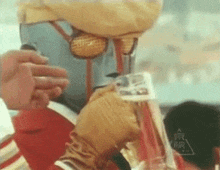 a man in a robot costume is holding a glass of water .