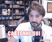 a man sitting in front of a microphone with the words ca etonne qui