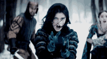 a group of people are standing in the snow and one of them has a sword in her hand