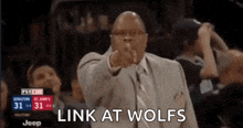 a man in a suit and tie is pointing at the camera with the words link at wolves written below him