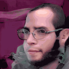 a close up of a man wearing glasses with a purple background