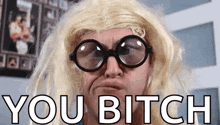 a man wearing glasses and a blonde wig is making a funny face and says you bitch .