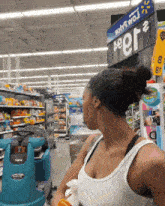 a woman in a white tank top is standing in a store under a sign that says peer 2