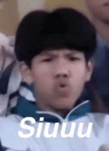 a young boy is making a funny face while sitting in a crowd .