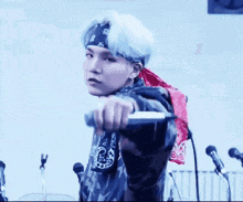 a man wearing a bandana is holding a microphone in his hand