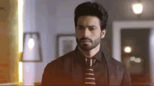 a man with a beard is wearing a black shirt and tie and standing in a room .