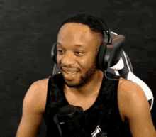 a man wearing headphones and a tank top is sitting in a chair .