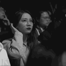 a black and white photo of a woman wearing glasses and a hoodie
