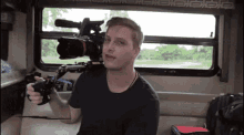 a man in a black shirt is holding a camera on a stand