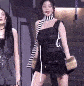 a woman in a black dress with a striped scarf around her neck is dancing on a stage .