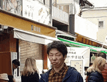 a man in a plaid shirt stands in front of a store with chinese writing