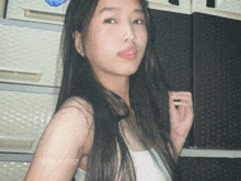 a woman with long black hair is standing in front of a stack of plastic drawers and a sign that says ' bb '