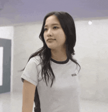 a woman with long black hair is wearing a white shirt