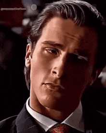a man in a suit and tie is looking at the camera .