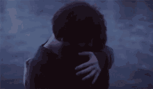 a man and a woman are hugging each other in front of the ocean .