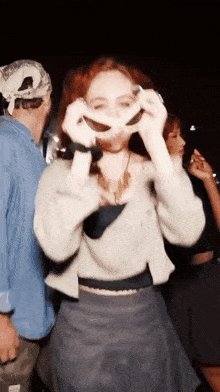 a woman in a white sweater is holding a pair of sunglasses