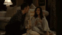 a man and a woman sit on a couch with a bottle of jameson
