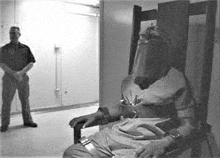a man is sitting in a electric chair with a mask on his head .