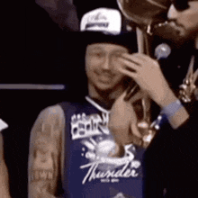 a man wearing a thunder jersey is holding a trophy in his hand .