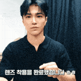 a man wearing a black shirt with korean writing on the bottom