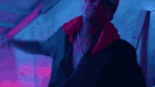 a man wearing a red jacket and a black shirt is dancing in a dark room .