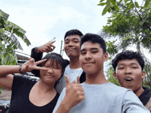 a group of young people are posing for a photo and one of them is giving a thumbs up