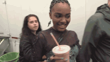 a woman holding a pink cup with a straw
