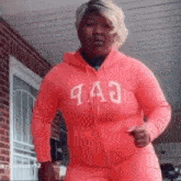 a woman is wearing a pink hoodie and pink sweatpants and is dancing .