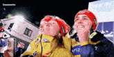 two people wearing red hats with the word altitude on them looking up