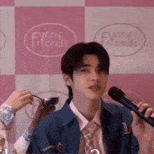 a man is holding a microphone in front of a pink and white checkered background that says funny friends