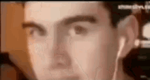a close up of a man 's face wearing ear buds .