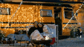 a man and a woman are sitting in front of a yellow van